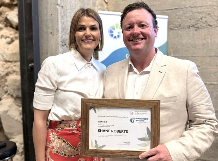 Photo of two adults holding an award