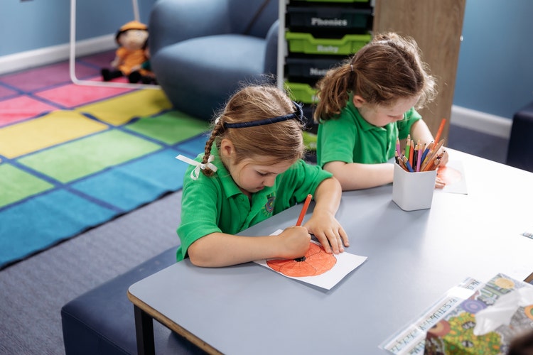 Photo of two students seated at a desk colouring in