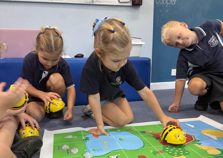 Image of three young students playing on the floor with robots