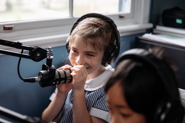 Image of student speaking in to a podcast microphone