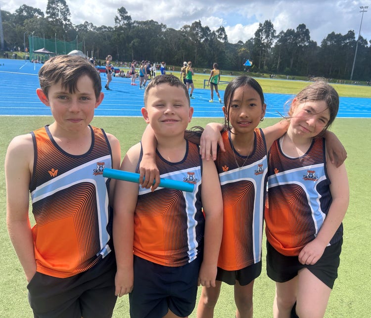 Image of four children in Upper Hunter Athletic singlets, holding a relay baton